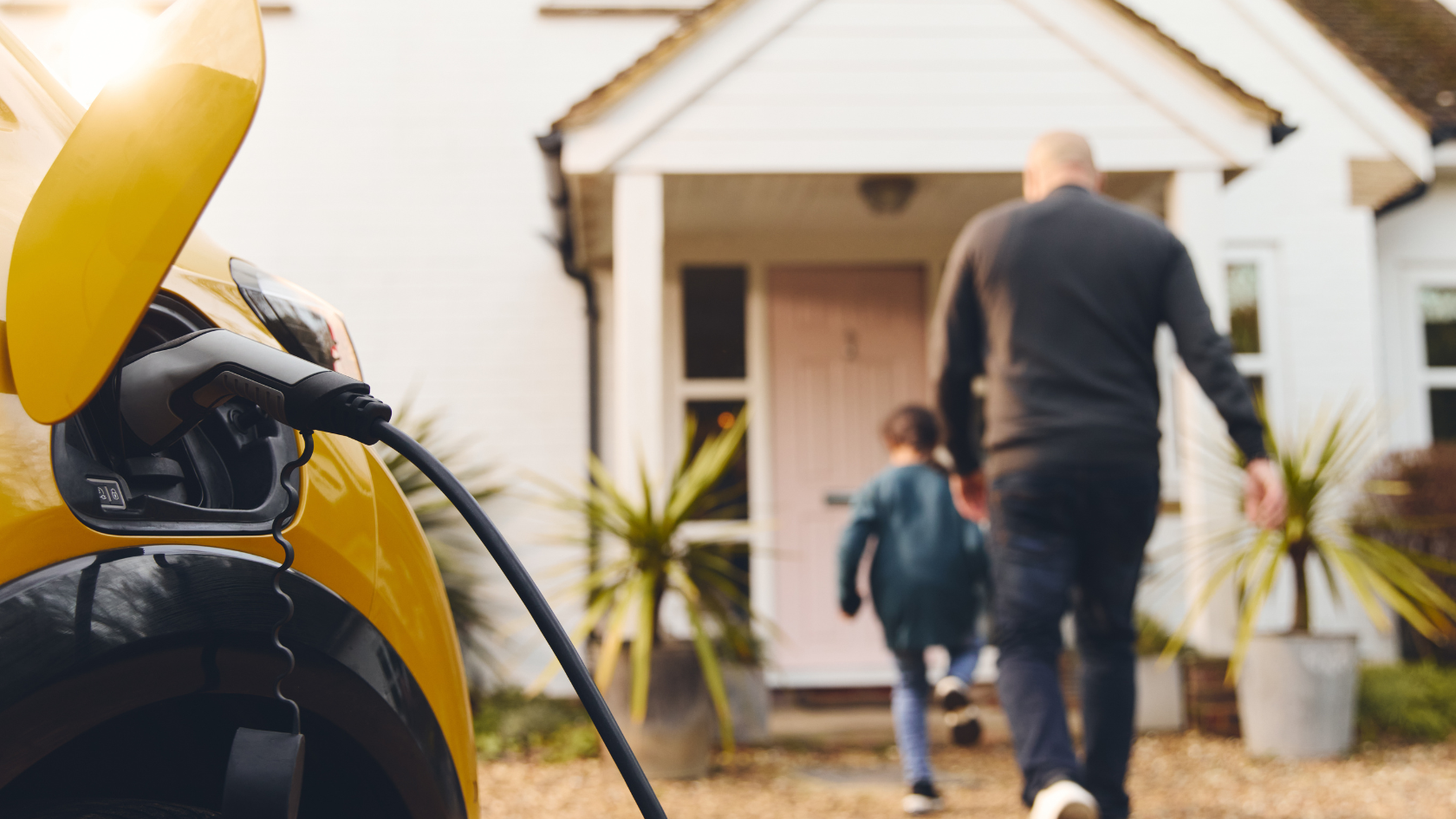 A man and a child are walking towards a yellow car