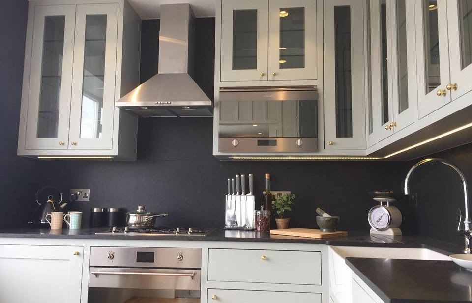 A kitchen with white cabinets and black walls